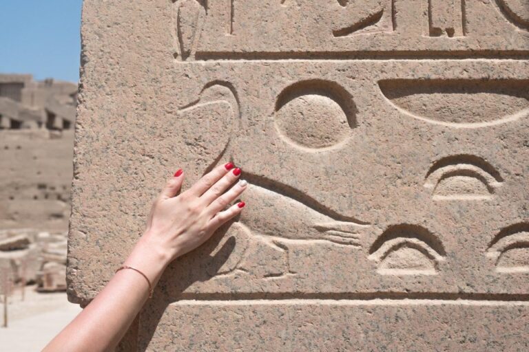 Hand an einem Relief mit Hieroglyphen