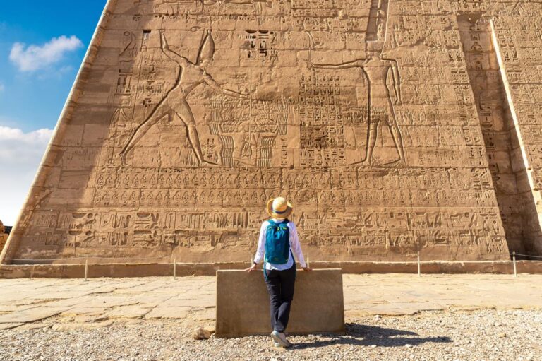 Besucher vor einer Tempelwand mit Reliefs in Luxor